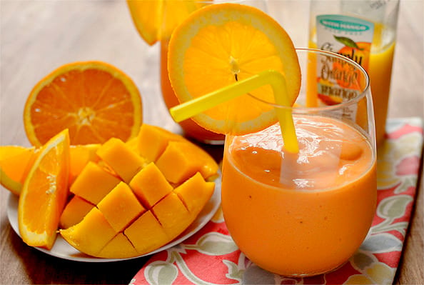 A vibrant Pineapple Mango Orange Smoothie served in a glass, garnished with fresh pineapple and mango slices, showcasing its rich tropical colors and creamy texture.
