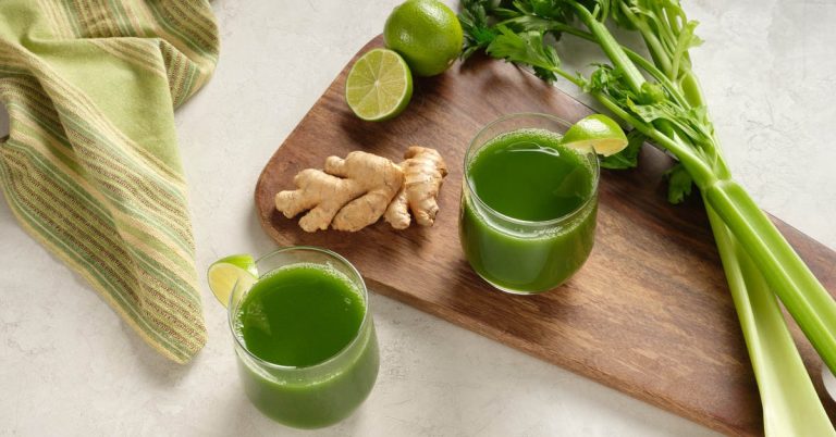 A glass of fresh celery ginger lime juice with a bright green color, served with sliced lime and ginger— a healthy drink that may help with blood sugar control after meals.